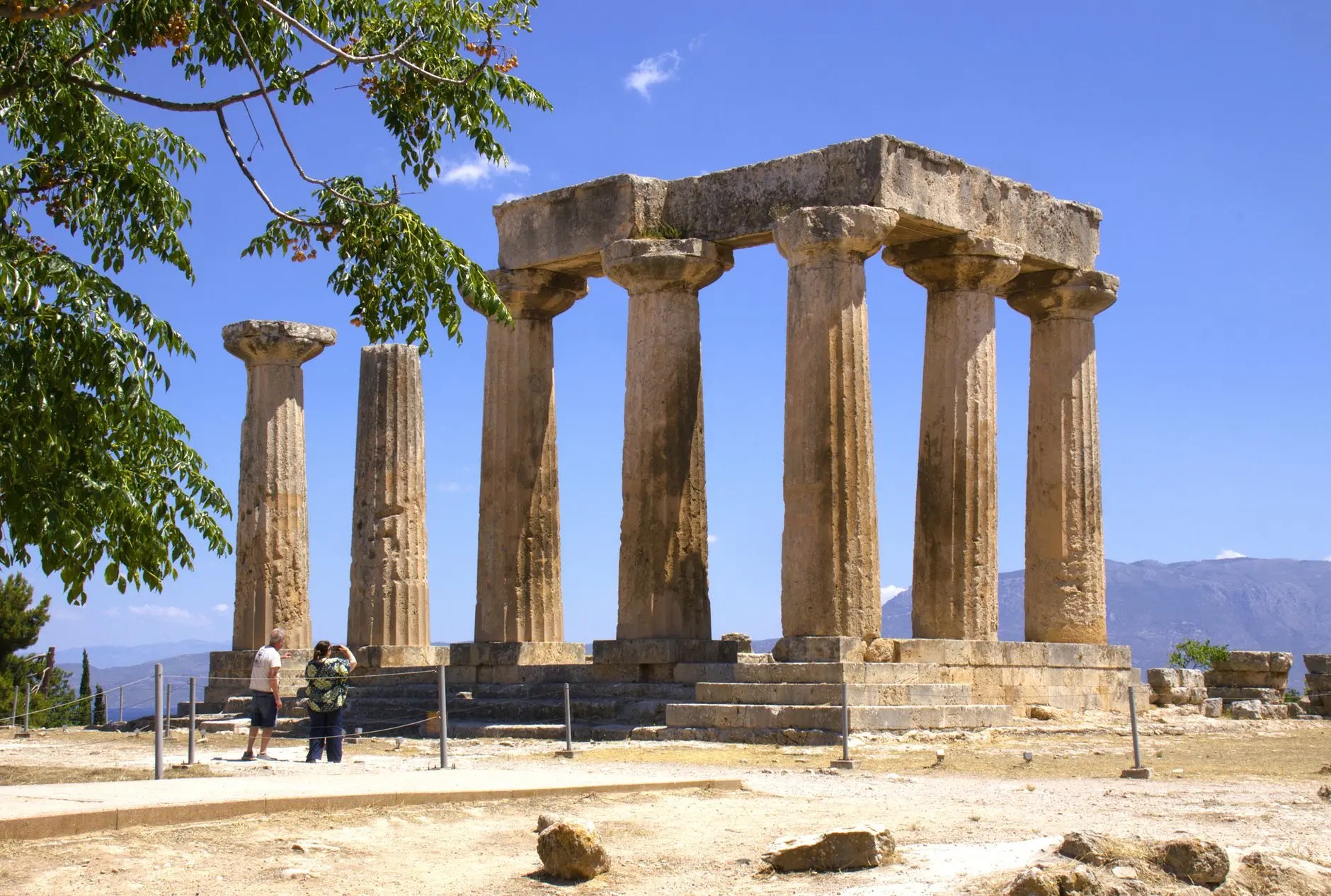Explore the Ancient Corinth Temple, showcasing classic Greek architecture under a clear summer sky.